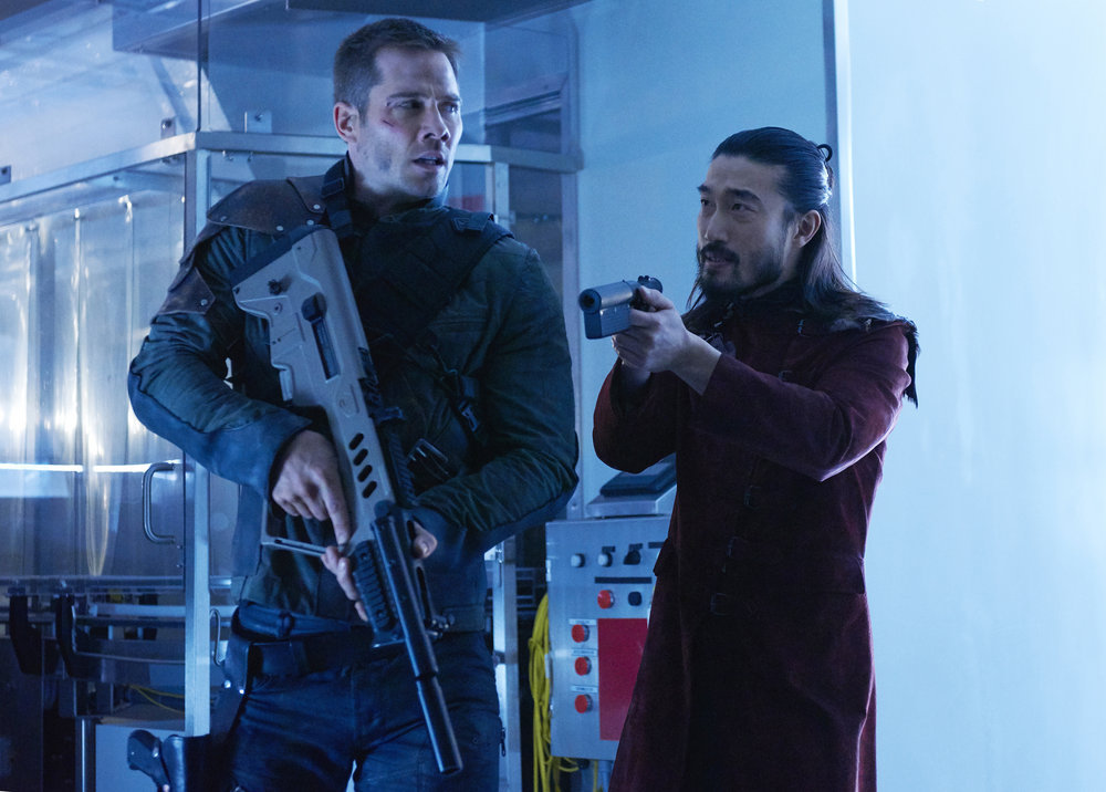 KILLJOYS -- "Dutch and the Real Girl" Episode 201 -- Pictured: (l-r) Luke Macfarlane as D'Avin, Sean Baek as Fancy Lee -- (Photo by: Steve Wilkie/Syfy/Killjoys II Productions Limited)